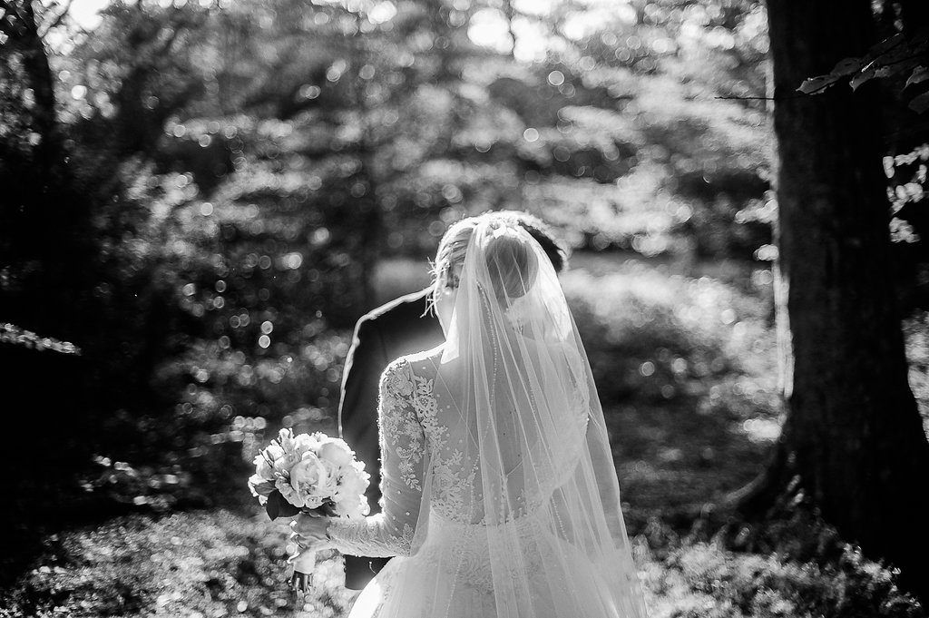 Bride and groom sharing a kiss among trees in black and white forest portrait.