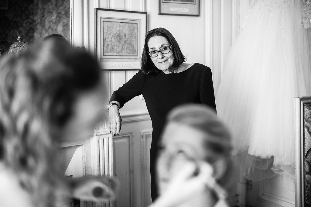 Woman in black top smiling while overseeing bridal preparations in an elegant room.