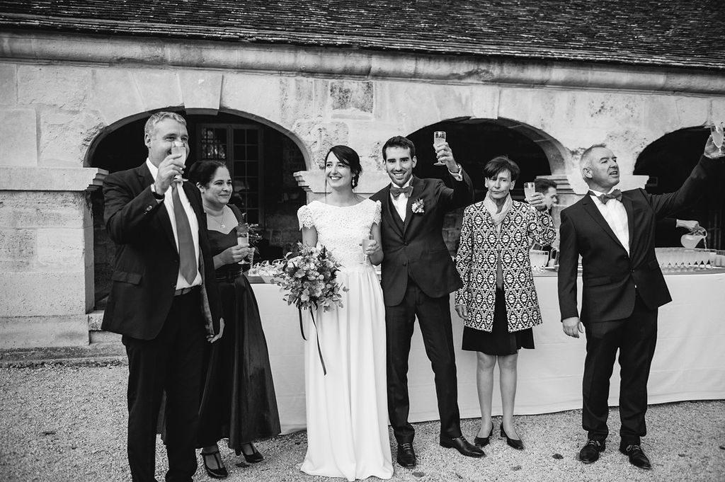 Black and white photo of bride, groom, and family posing together at wedding reception.