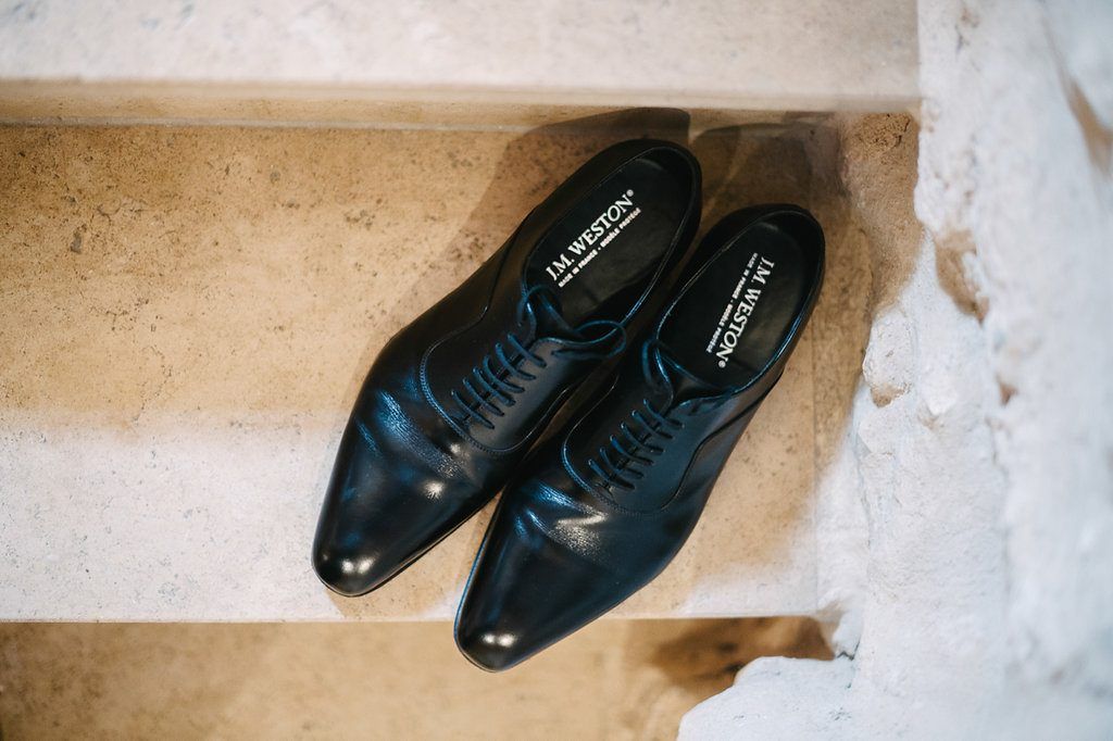 Classic black leather Oxford dress shoes placed on marble steps for a wedding day.