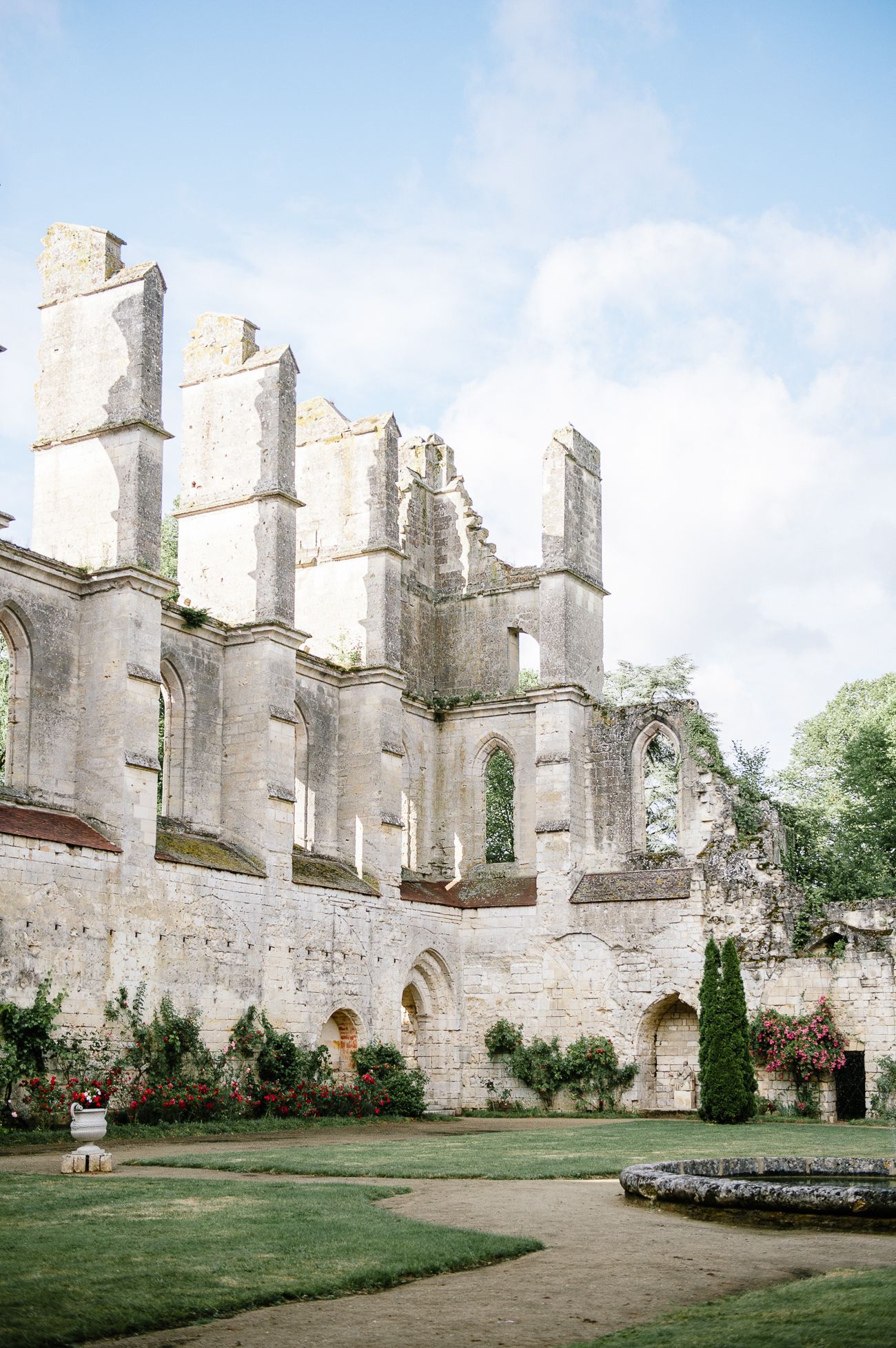Stunning ruins of a Gothic stone abbey with manicured gardens under a partly cloudy sky.