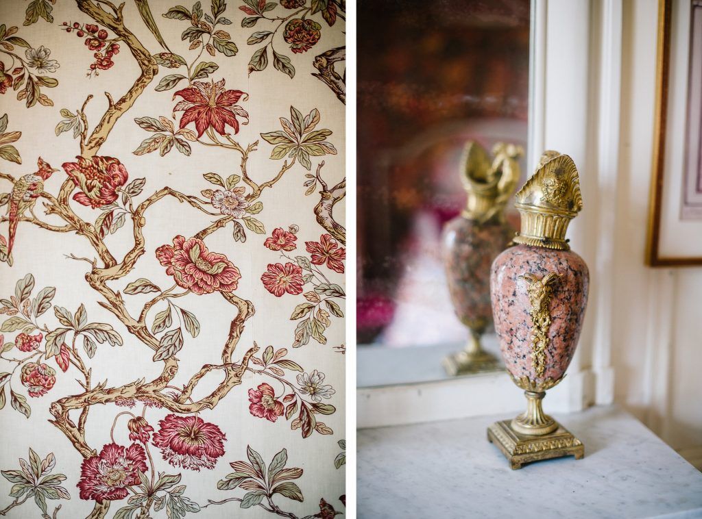Vintage floral wallpaper beside an ornate gold and pink decorative vase on a mantelpiece.