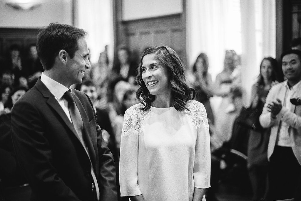 Bride and groom share a joyful moment smiling at each other during wedding ceremony.