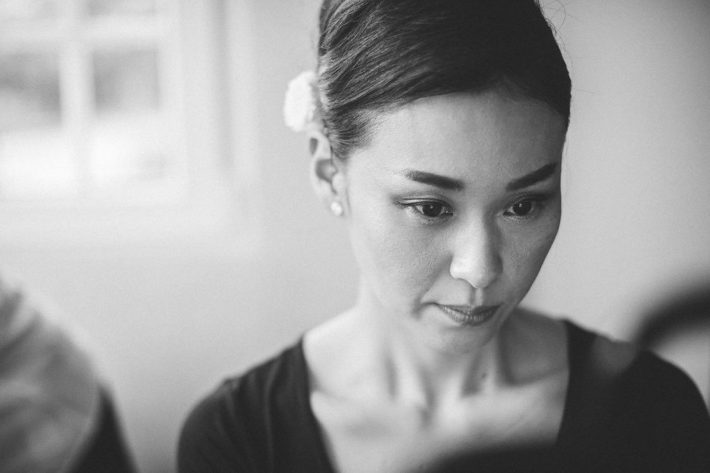 Black and white portrait of an elegant Asian woman looking down with a white flower in her hair.