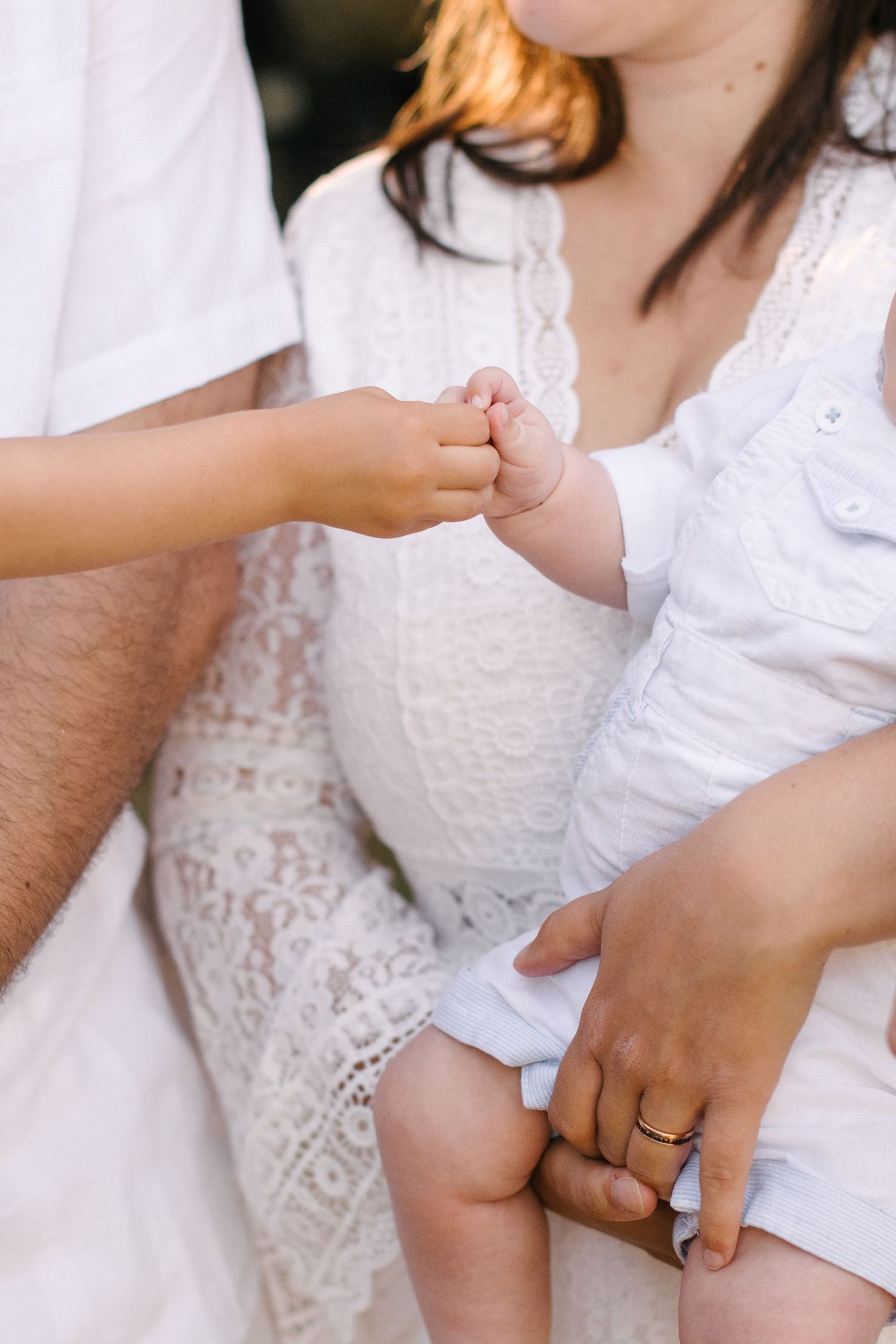Close-up of baby's tiny hand held by parents during outdoor family photoshoot.