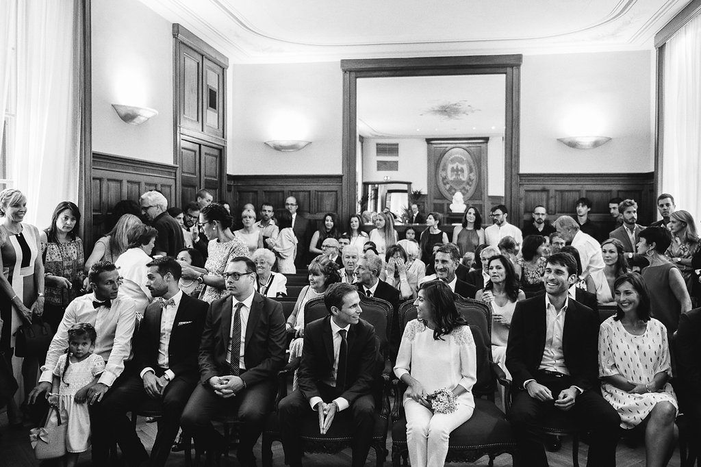 Wedding guests seated in elegant room during civil ceremony black and white photo.