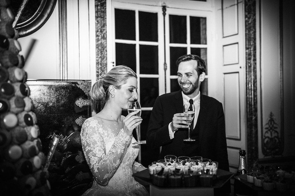 Black and white photo of bride and groom sharing champagne toast at elegant wedding reception.