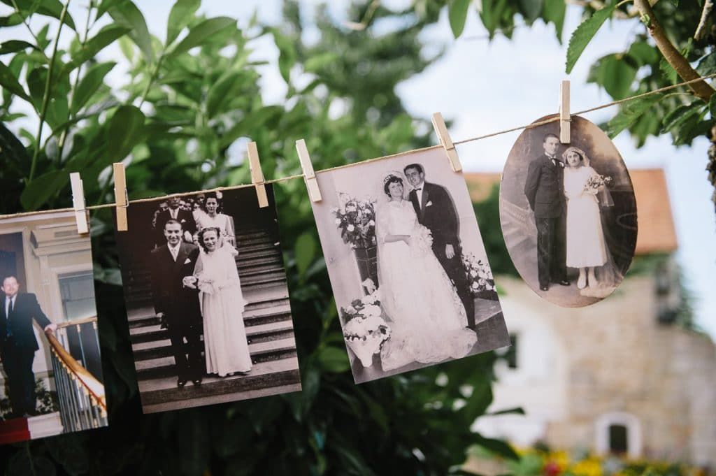 Vintage black and white wedding photos hanging on a string outdoors.