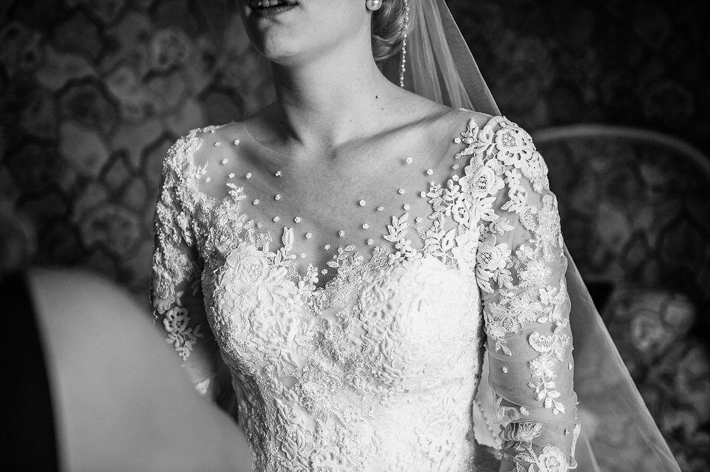 Close-up black and white portrait of bride in lace wedding gown with pearl embellishments and veil.