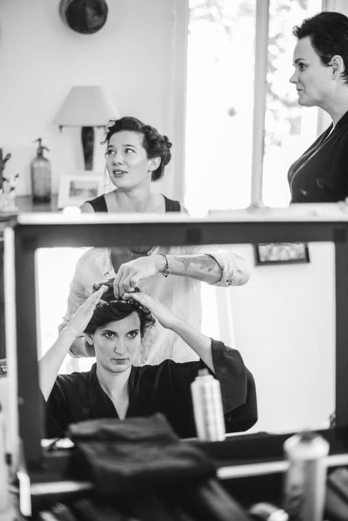 Black and white photo of a bride getting her hair styled by a hairdresser before her wedding.