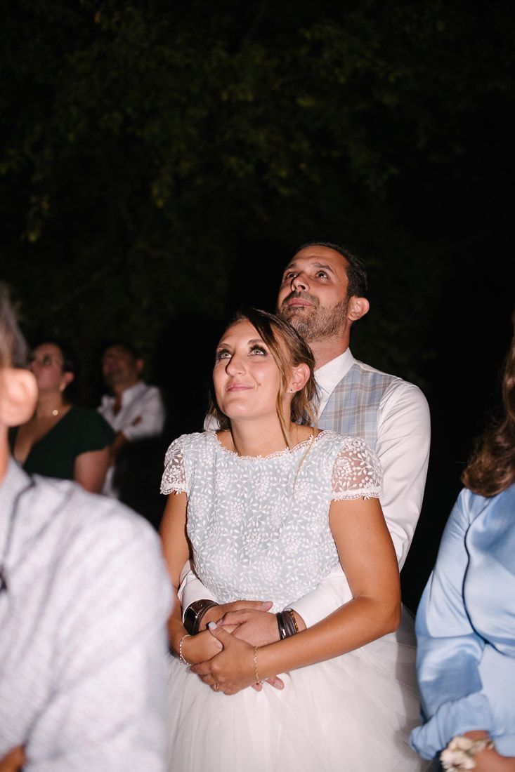 Bride and groom looking up together at night during outdoor wedding reception celebration.
