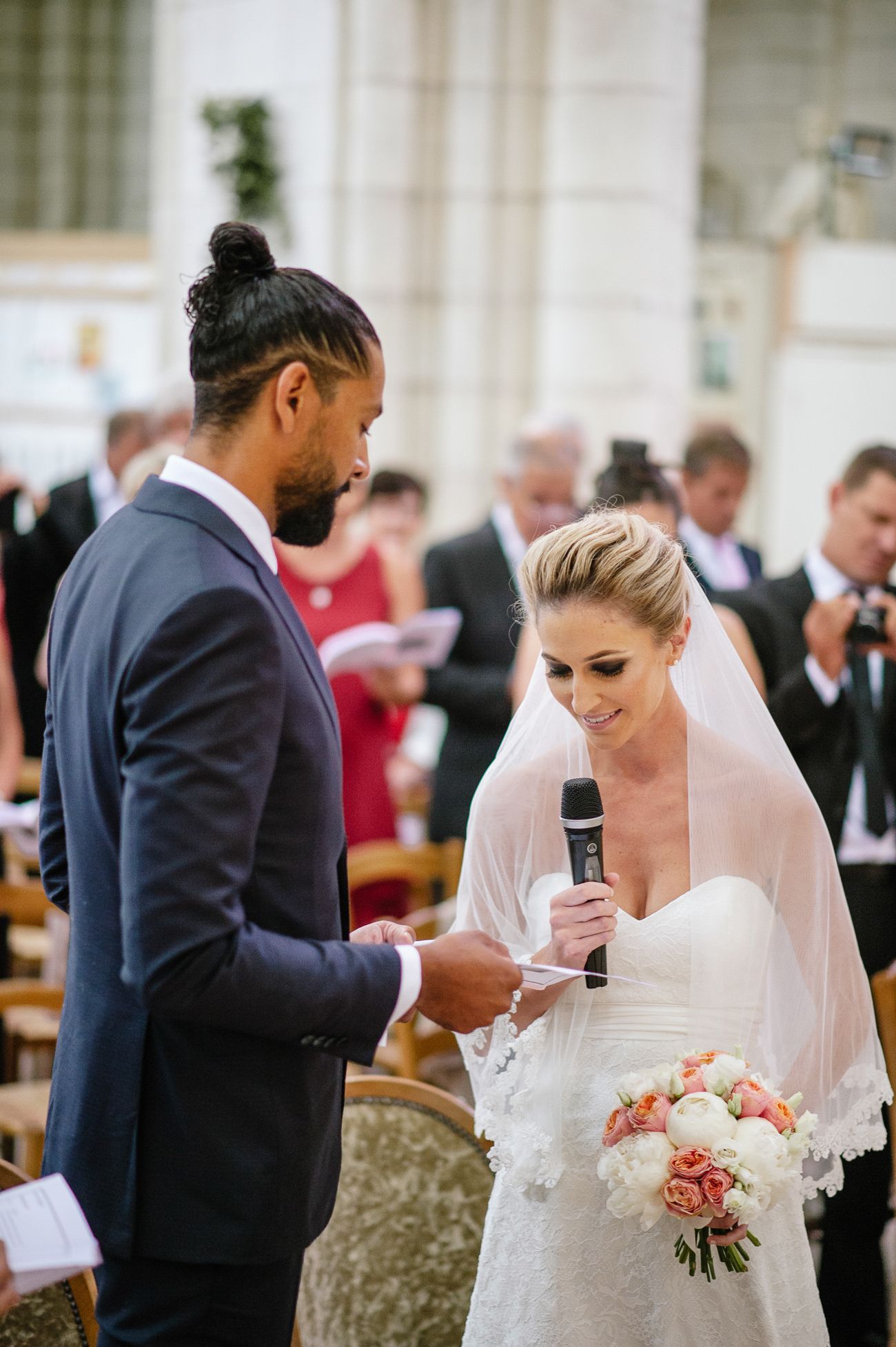 Bride reads vows holding bouquet while groom listens during elegant wedding ceremony.