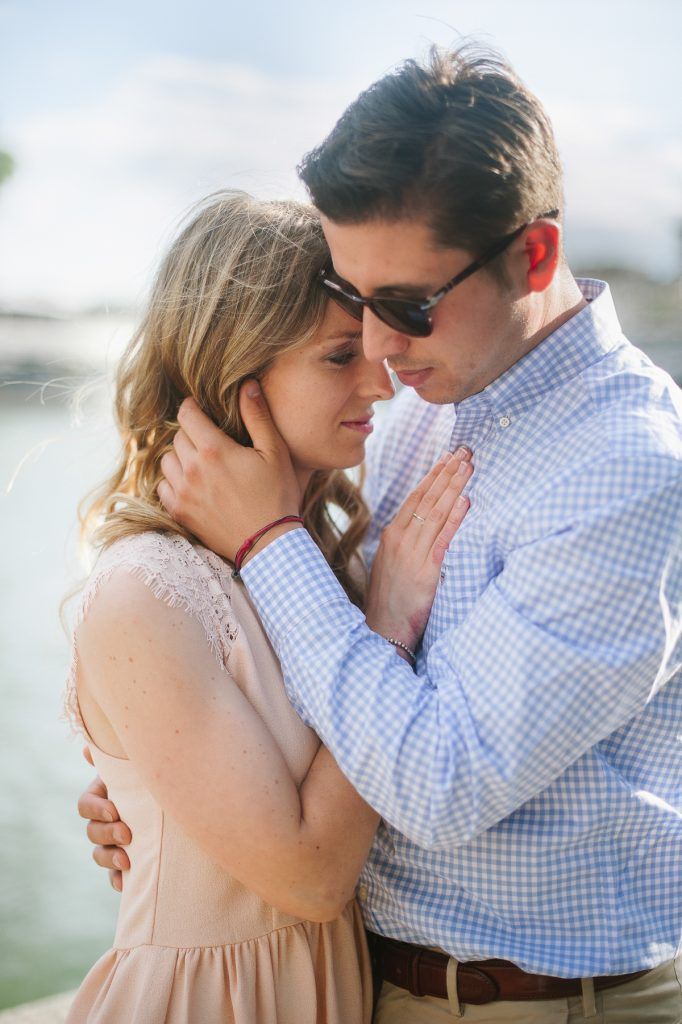 Intimate close-up of a couple tenderly embracing near a sunlit river in Paris.