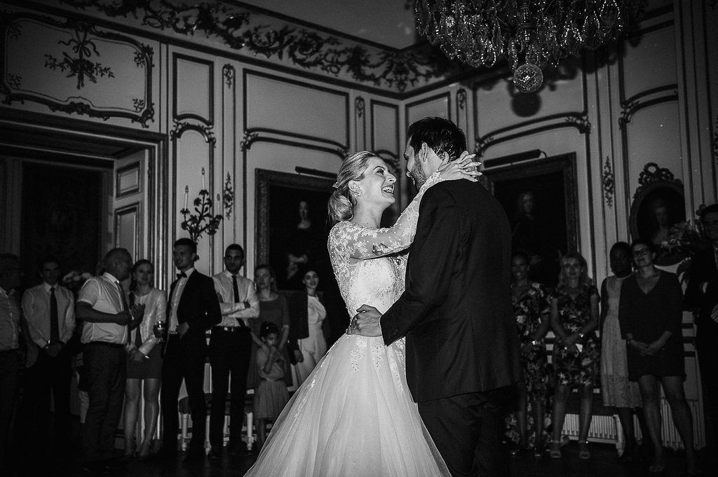 Bride and groom share romantic first dance in black and white photo at elegant French chateau wedding reception.