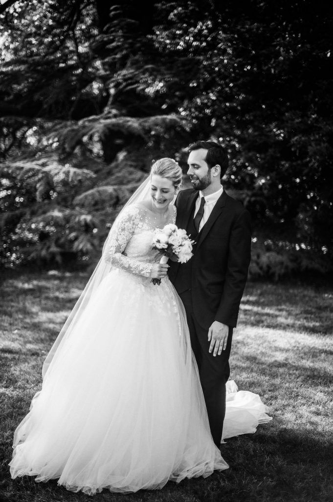 Bride and groom sharing intimate moment in garden, black and white wedding portrait.