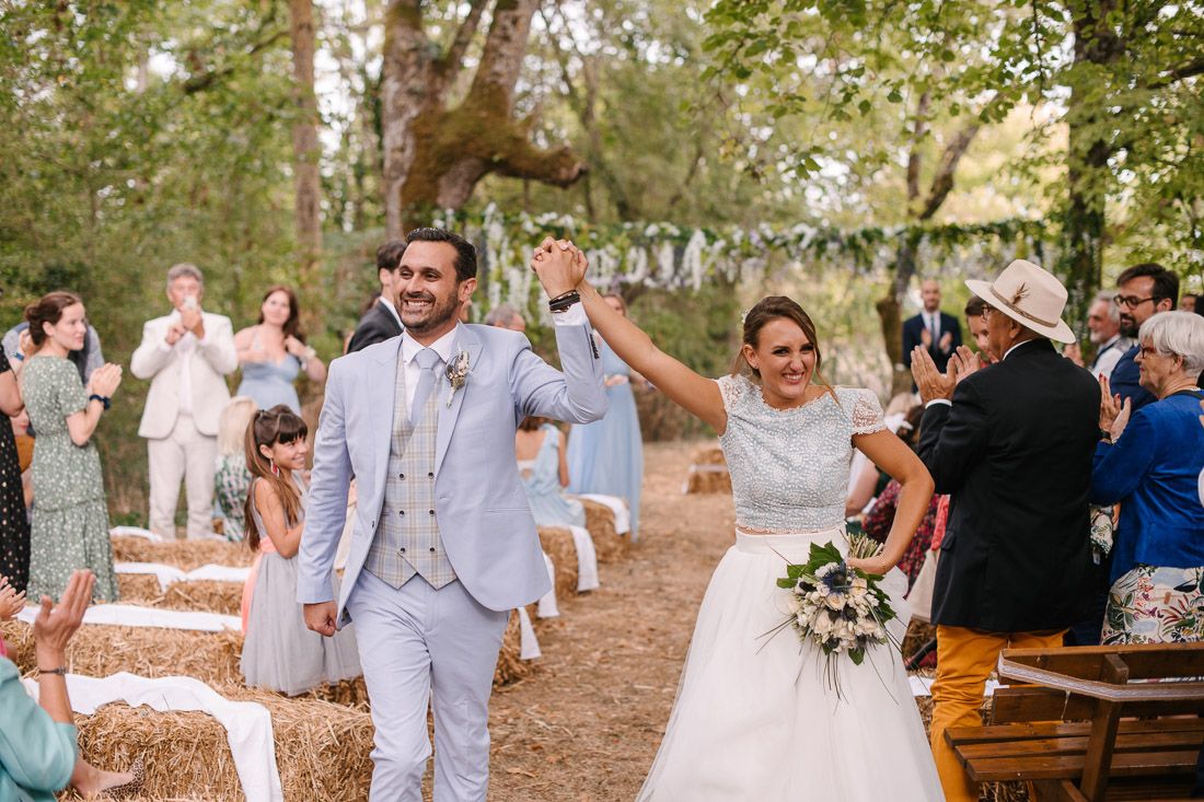 Joyful newlyweds celebrating their outdoor rustic wedding ceremony with cheering guests.
