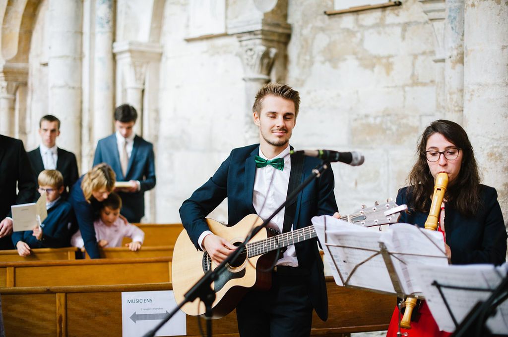 Live band performing at wedding ceremony with guitarist and flutist in church.