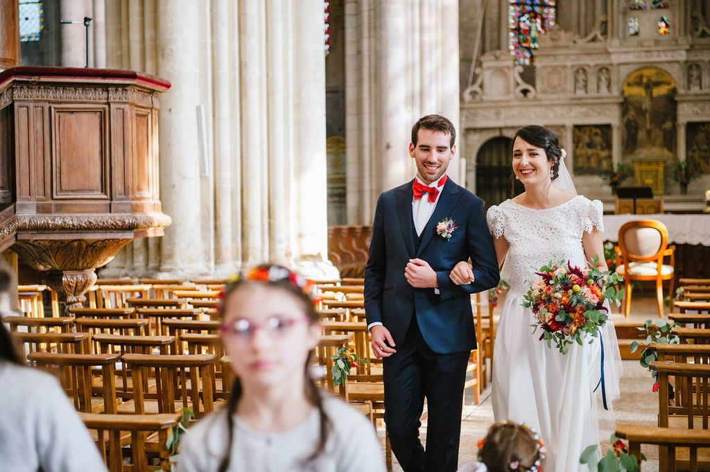 Bride and groom walk down the aisle together in a sunlit historic church after their ceremony.