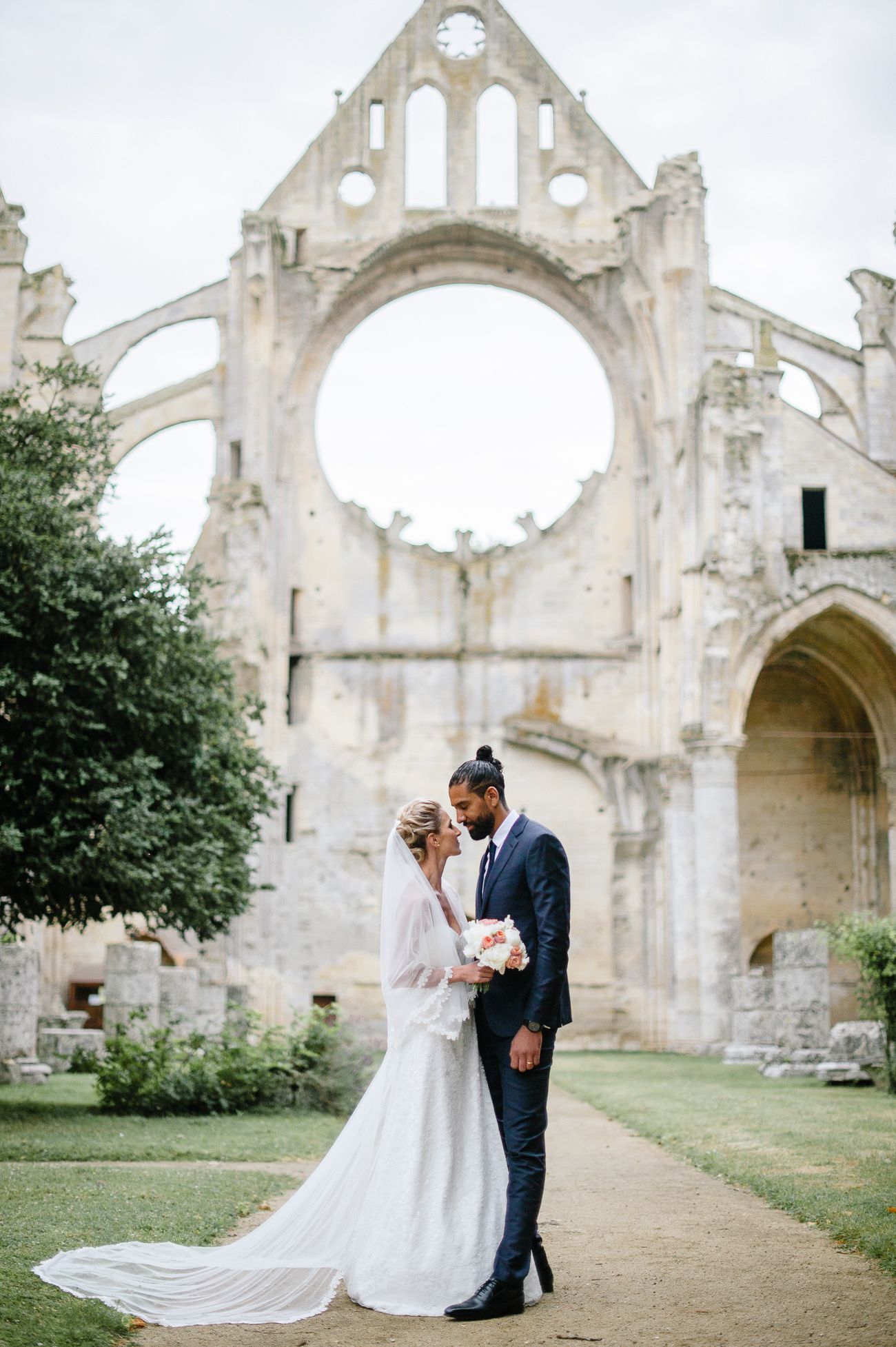 Bride and groom share a romantic moment before ancient Gothic abbey ruins on their wedding day.