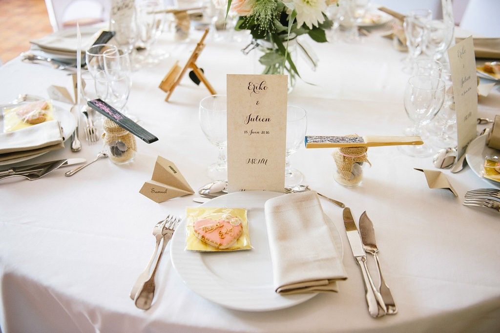 Elegant wedding reception table setting with white linens, personalized menu card, and folded napkins.