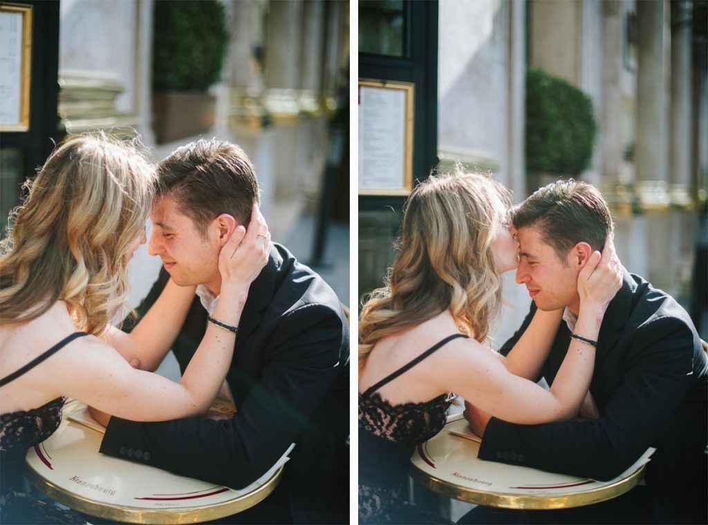 Romantic couple sharing an intimate moment at a classic Parisian cafe table, leaning close together.