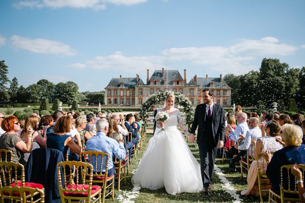 Bride and groom recessional walk through confetti at elegant French chateau garden wedding.