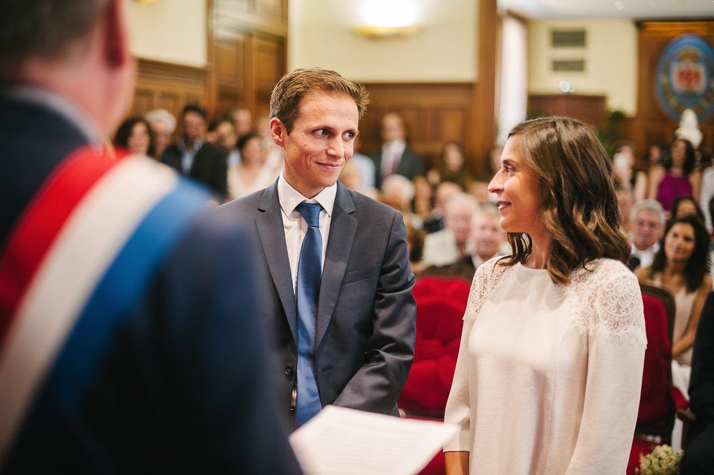 Bride and groom exchange smiles during their civil wedding ceremony at a formal venue.