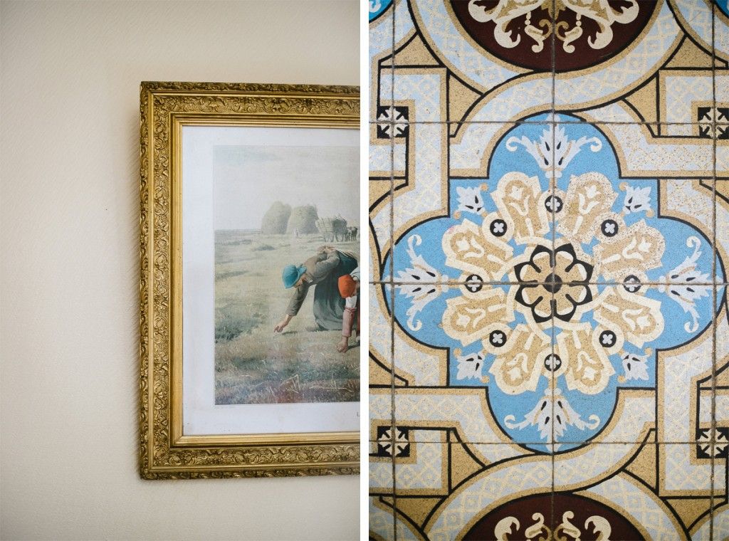 Decorative blue and gold ornate tile pattern beside framed pastoral artwork on wall.