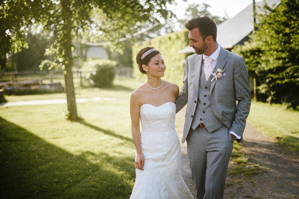 Bride and groom share a romantic glance while walking in golden sunlight on their wedding day.
