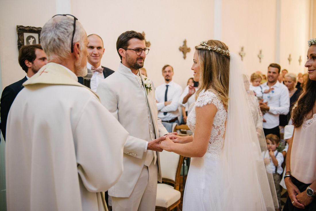 Bride and groom exchange vows at altar with officiant during intimate church wedding ceremony.
