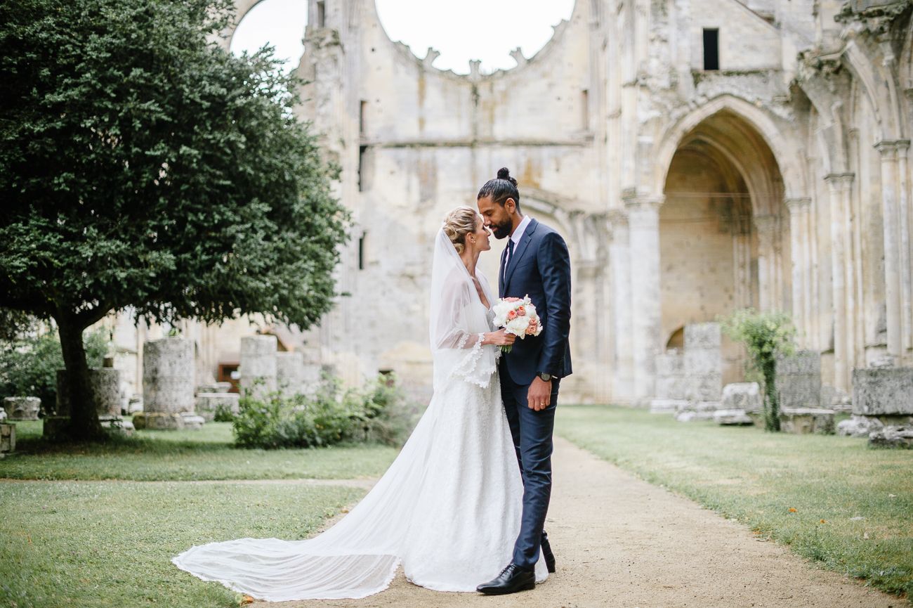 Bride and groom sharing a romantic moment in front of ancient stone ruins on their wedding day.