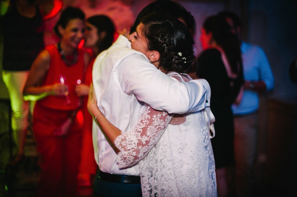 Bride and groom sharing intimate embrace on colorful wedding reception dance floor.