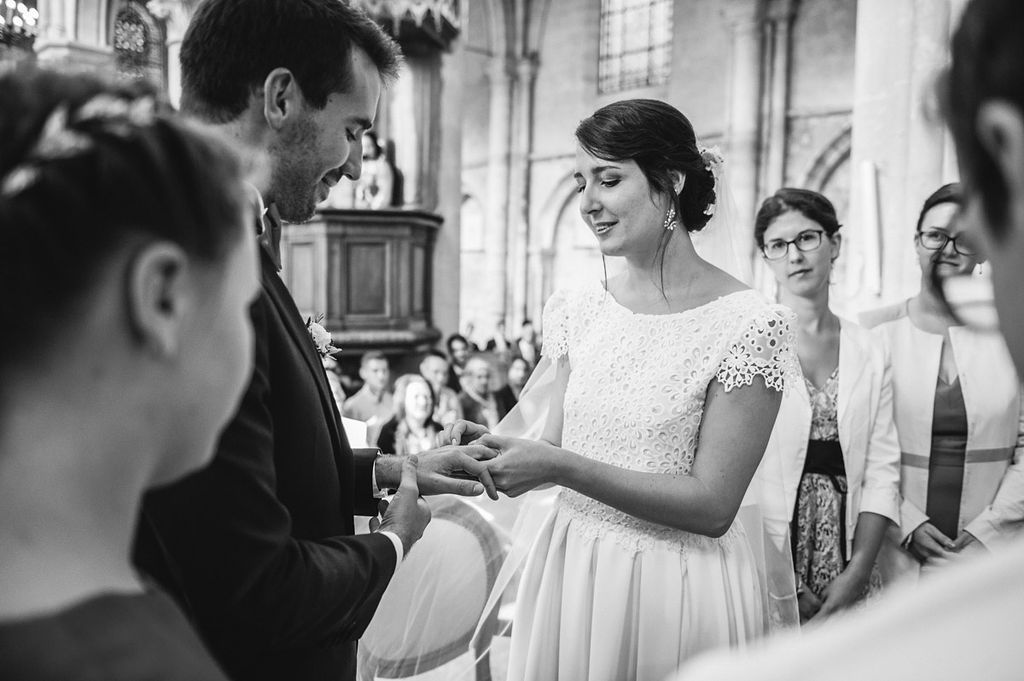 Bride and groom exchange rings during an elegant black and white church wedding ceremony.