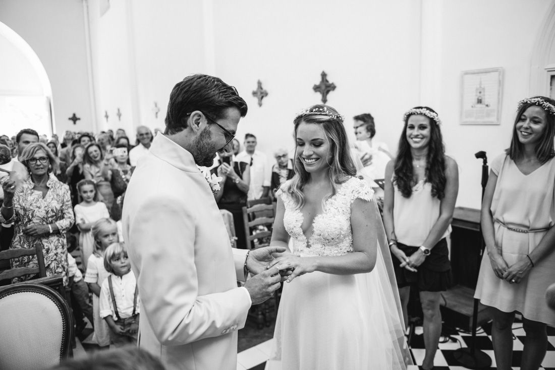 Bride and groom exchange rings during a church wedding ceremony in black and white photo.
