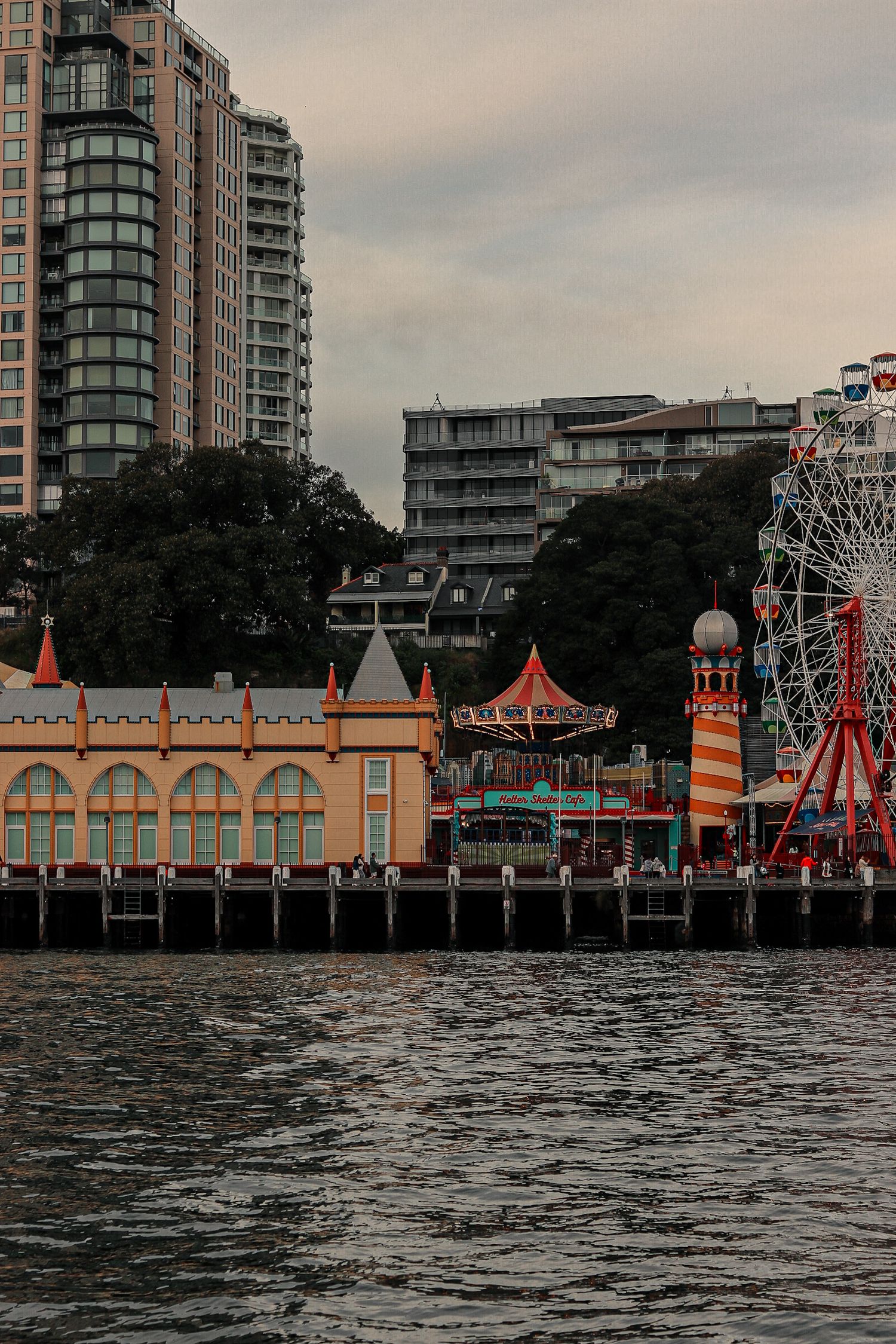Waterfront amusement park with colorful buildings and rides along the shoreline at dusk.