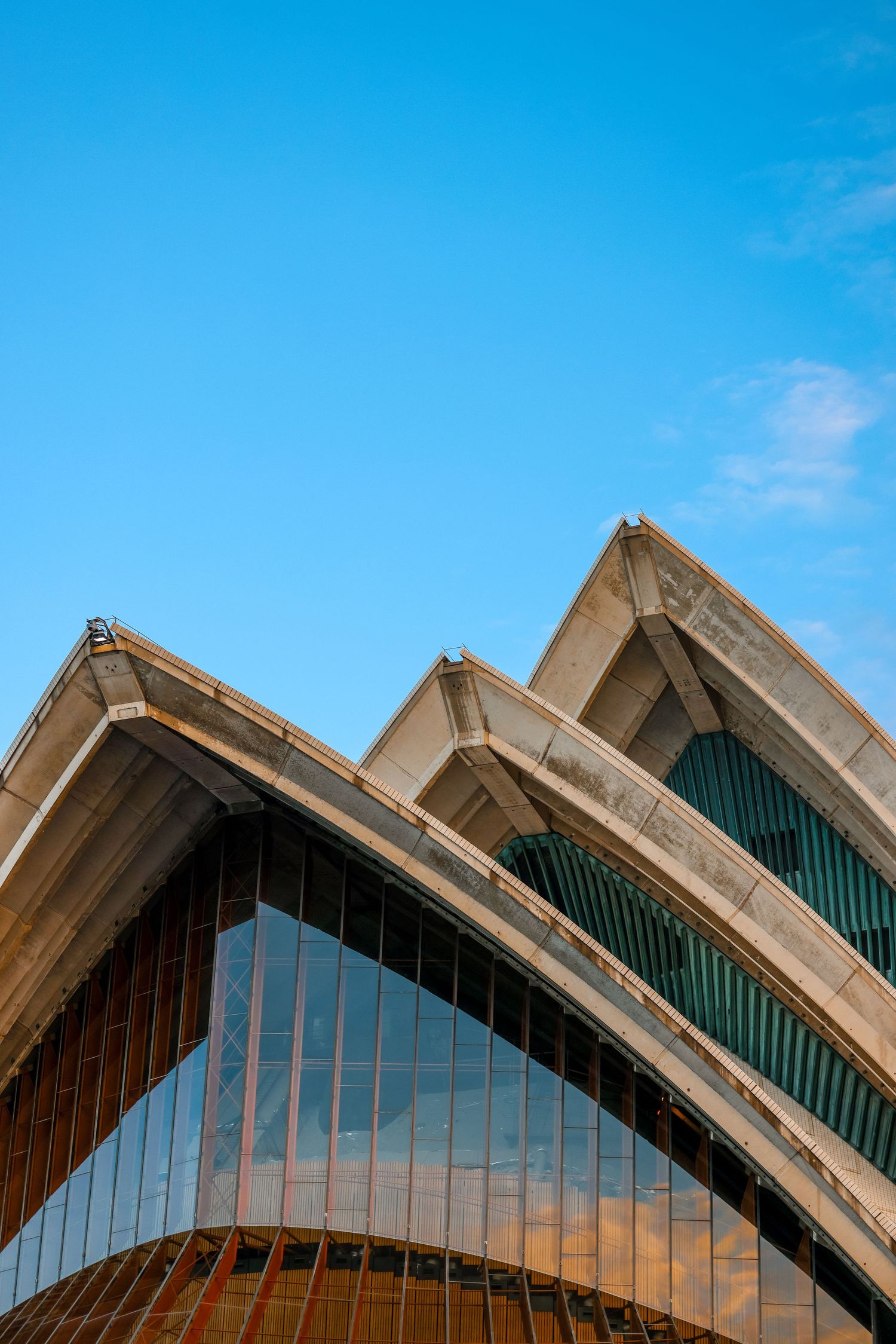 Architectural detail of Sydney Opera House's iconic sail-like roof structures against blue sky.