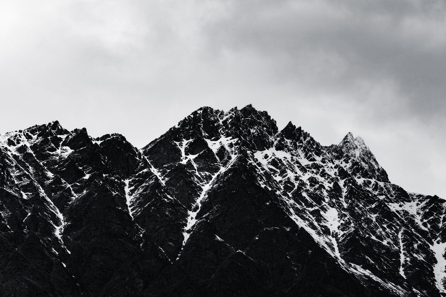 Dramatic black and white mountain range with snow-covered ridges.
