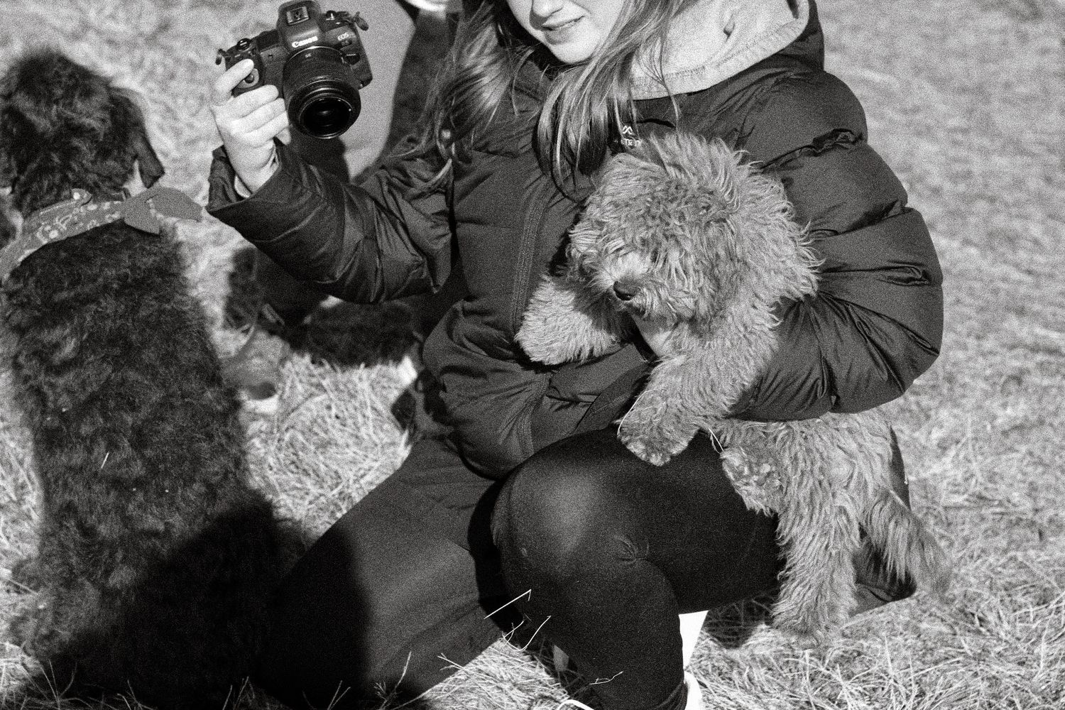 Black and white photo of someone playing with a fluffy dog in the snow.