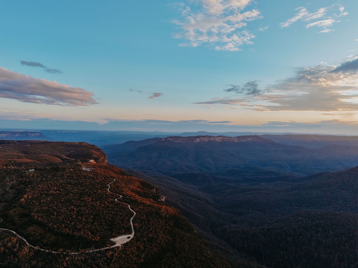Panoramic mountain vista with winding roads cutting through autumn-colored slopes.