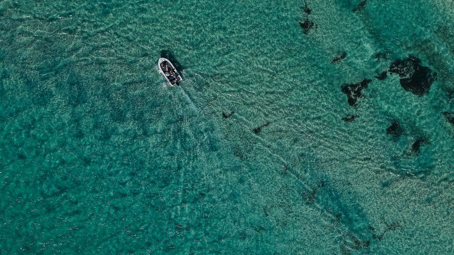 Drone view of turquoise coral reefs and shallow waters from above.