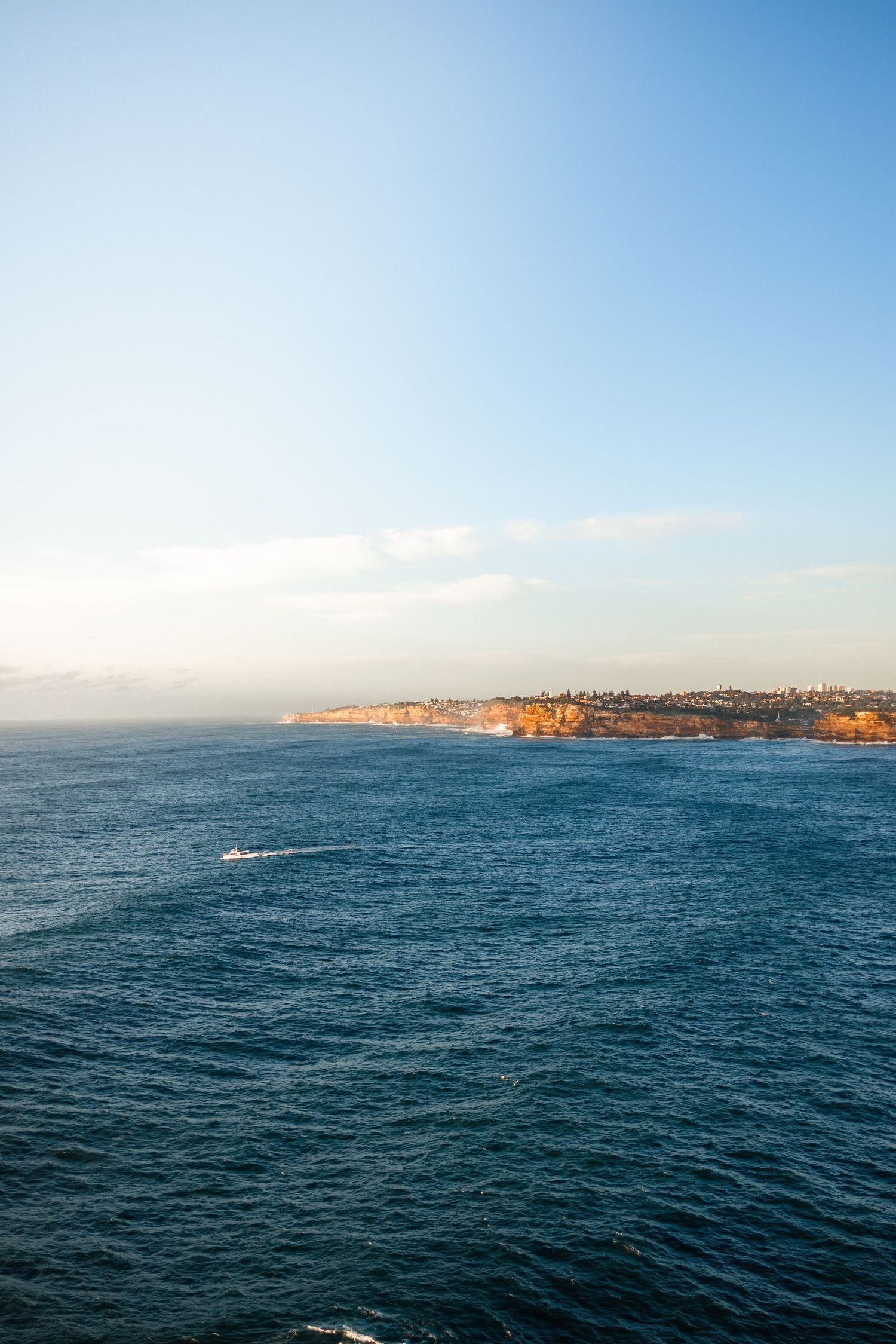 Panoramic view of deep blue ocean waters meeting distant coastal cliffs.