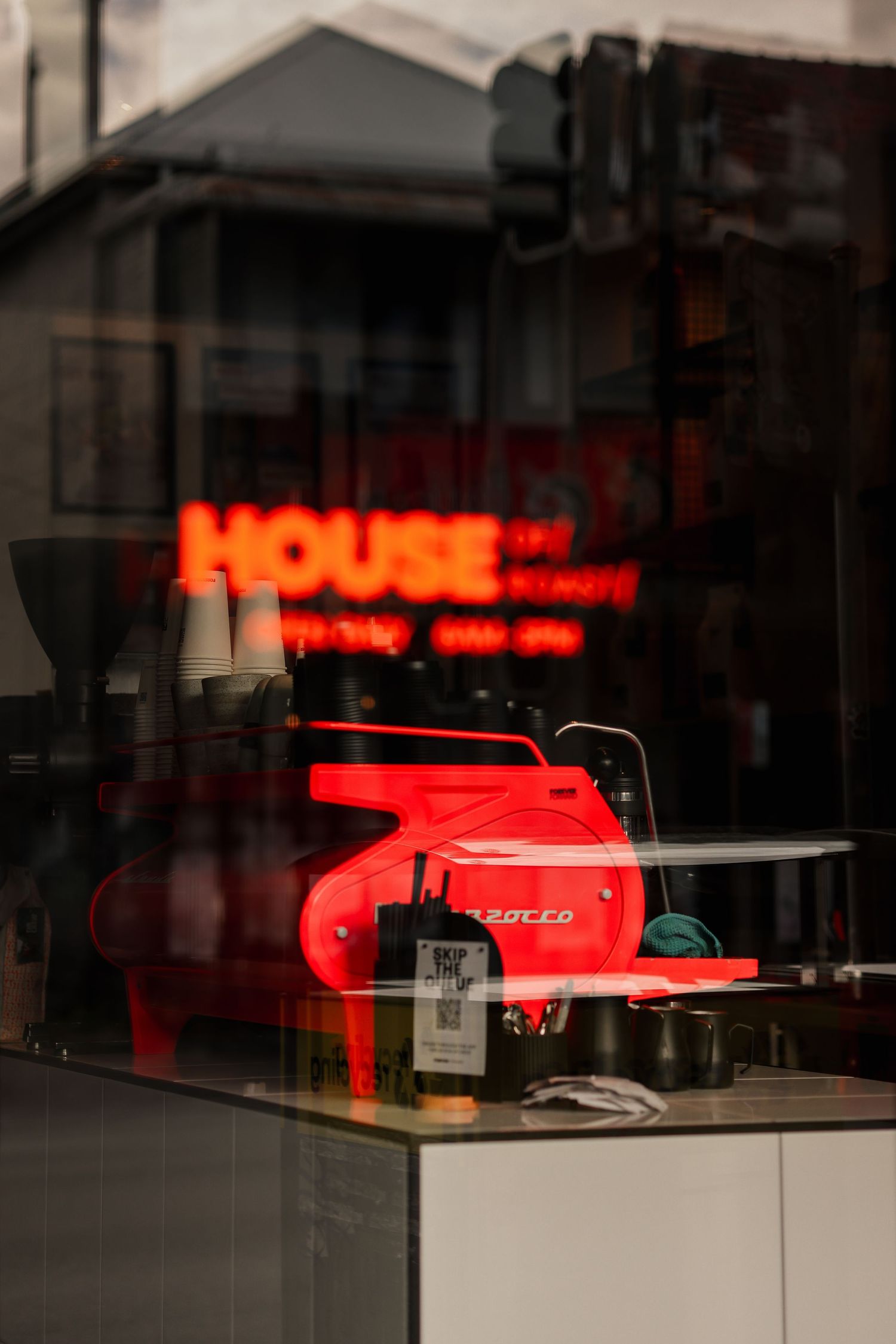 Red neon coffee machine seen through a coffee shop window