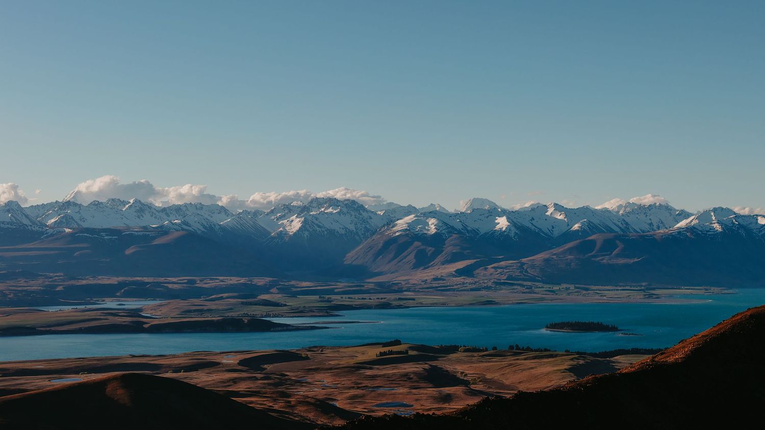 Snow-capped mountain ranges stretch across the horizon under a clear blue sky.