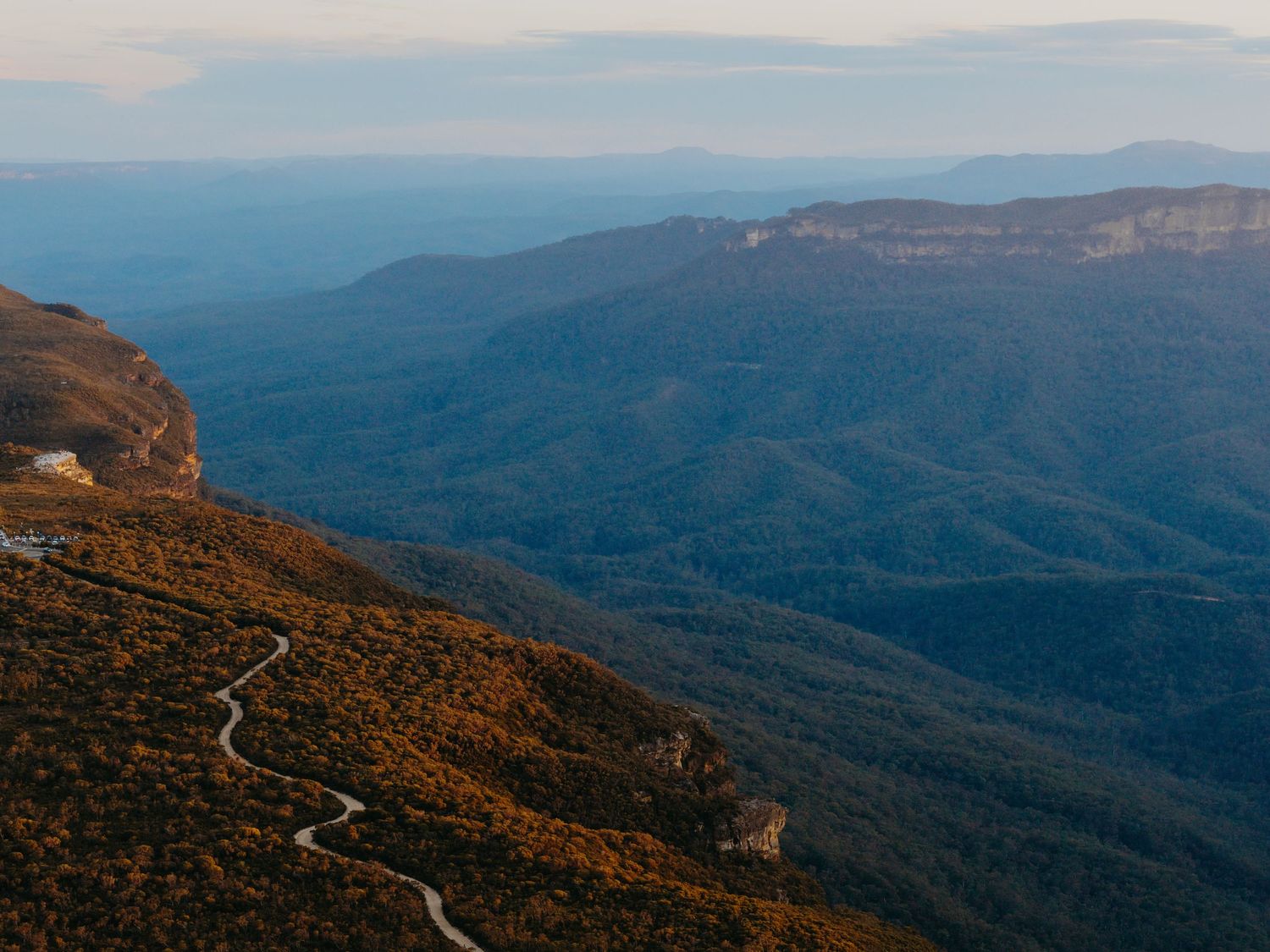 Aerial view of winding mountain roads through rugged autumn terrain.