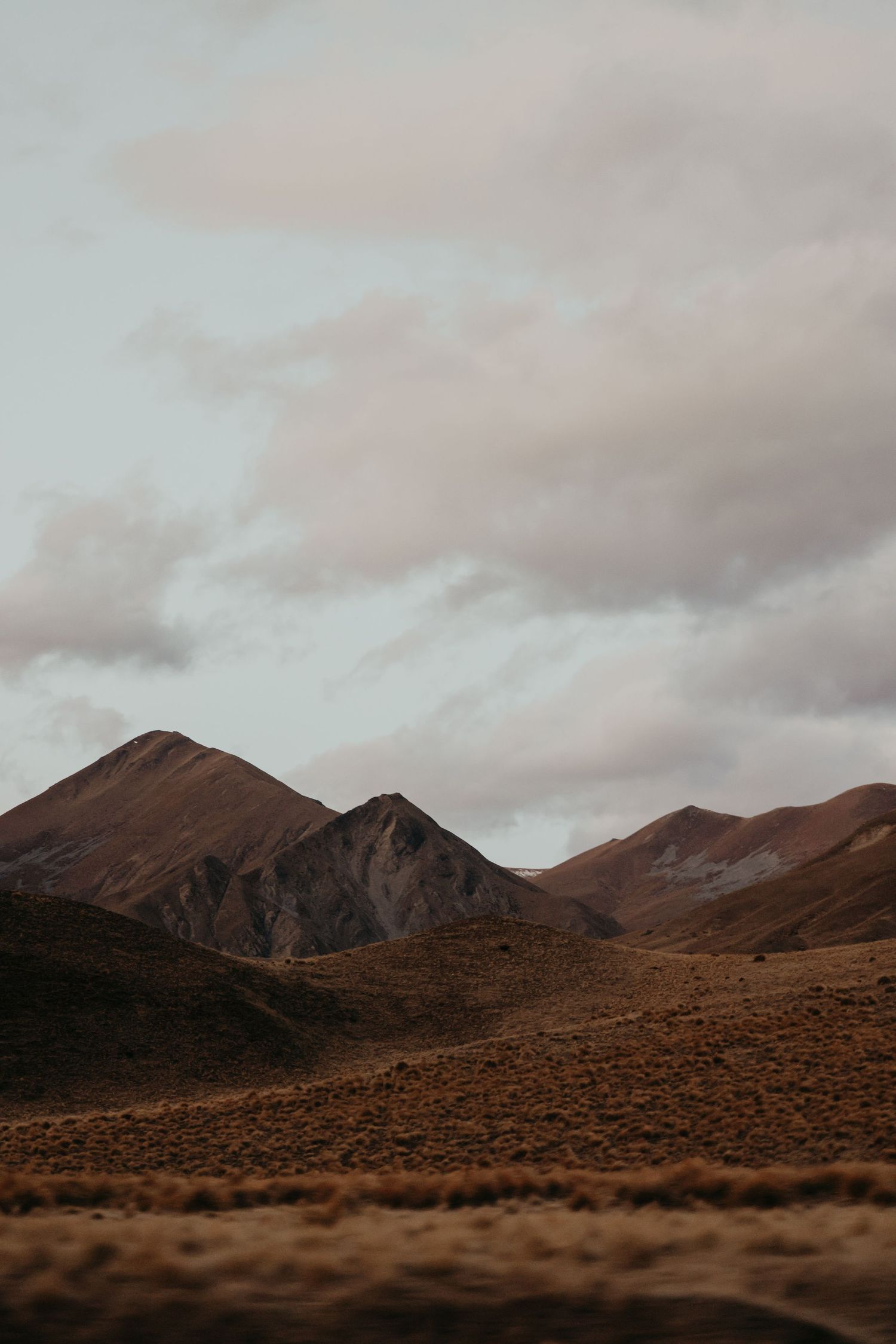 Brown desert mountains under moody cloudy skies at dusk.