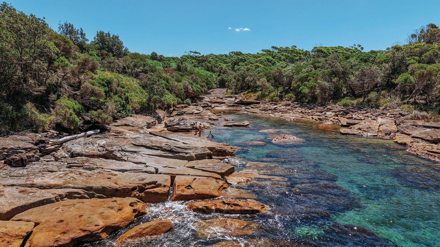 Rocky coastline with crystal clear turquoise waters and sandstone formations.