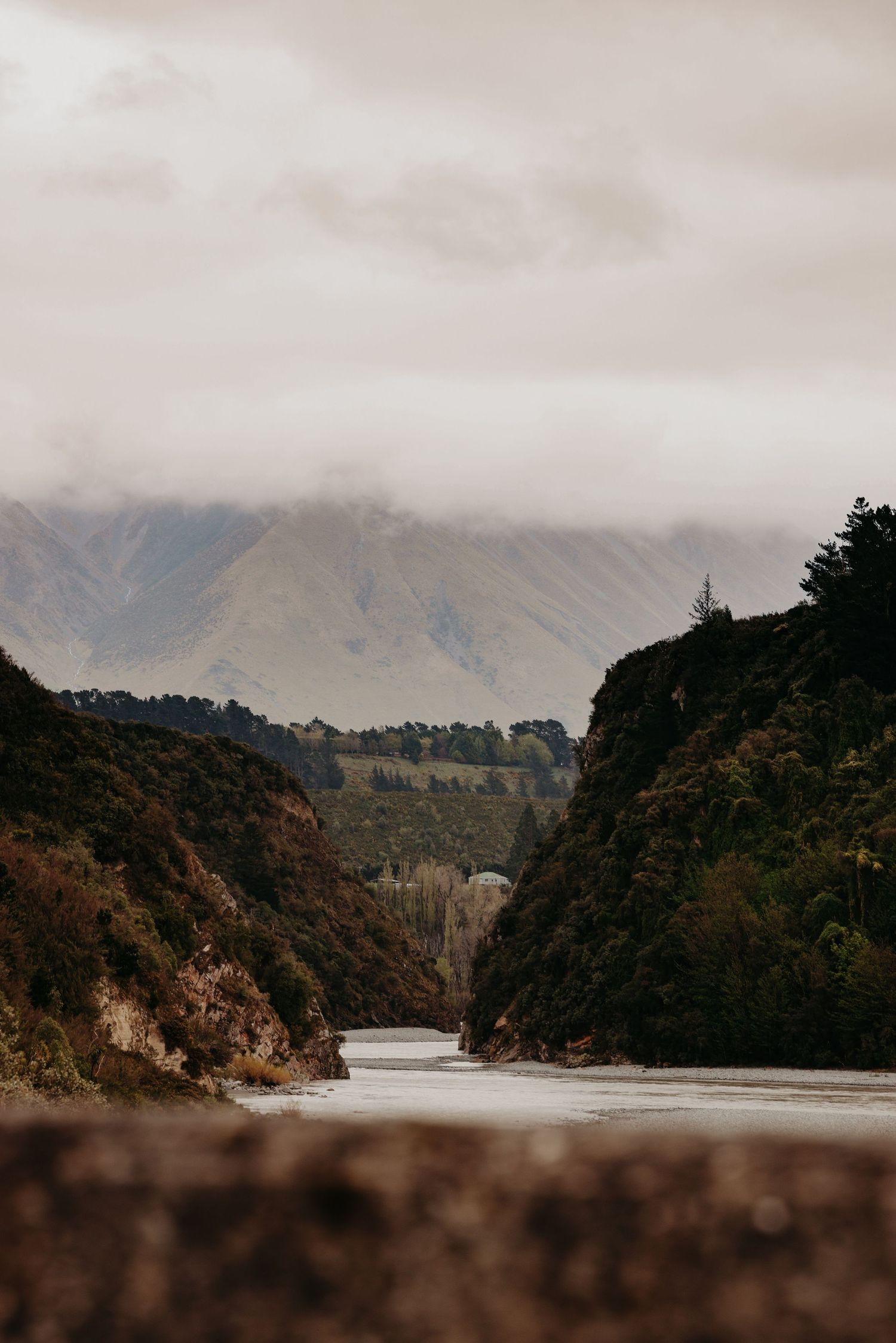 Misty river winding through steep cliffs and mountains in moody lighting.