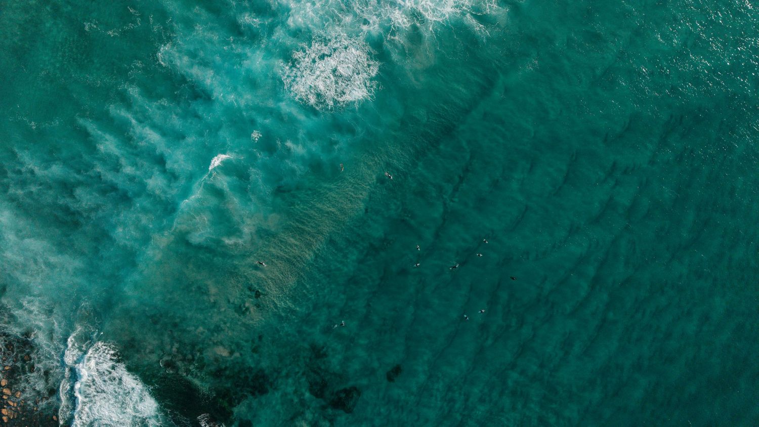 Aerial view of turquoise ocean waves with white foam patterns on the water surface.