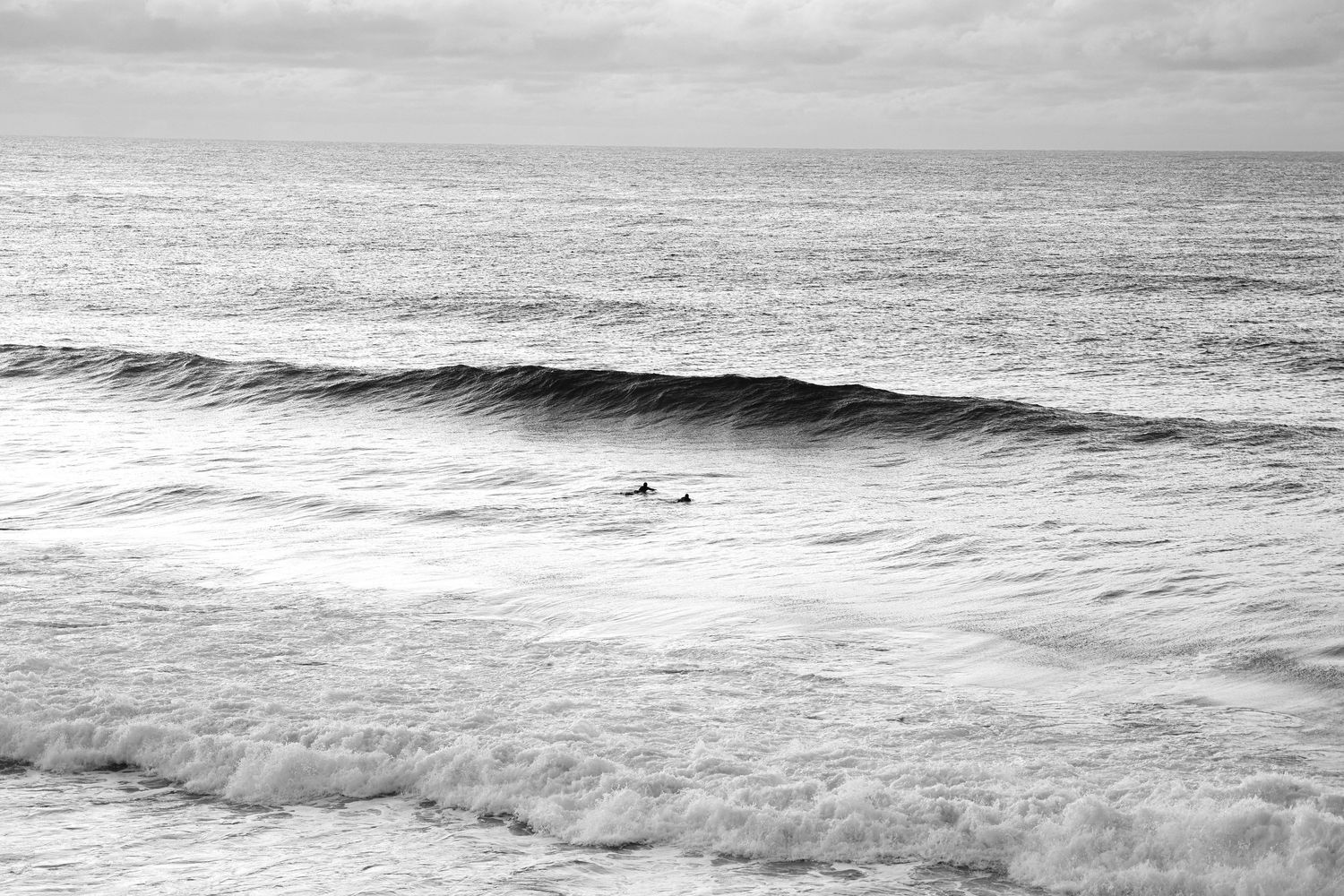 Monochromatic seascape showing rolling ocean waves under an overcast sky.