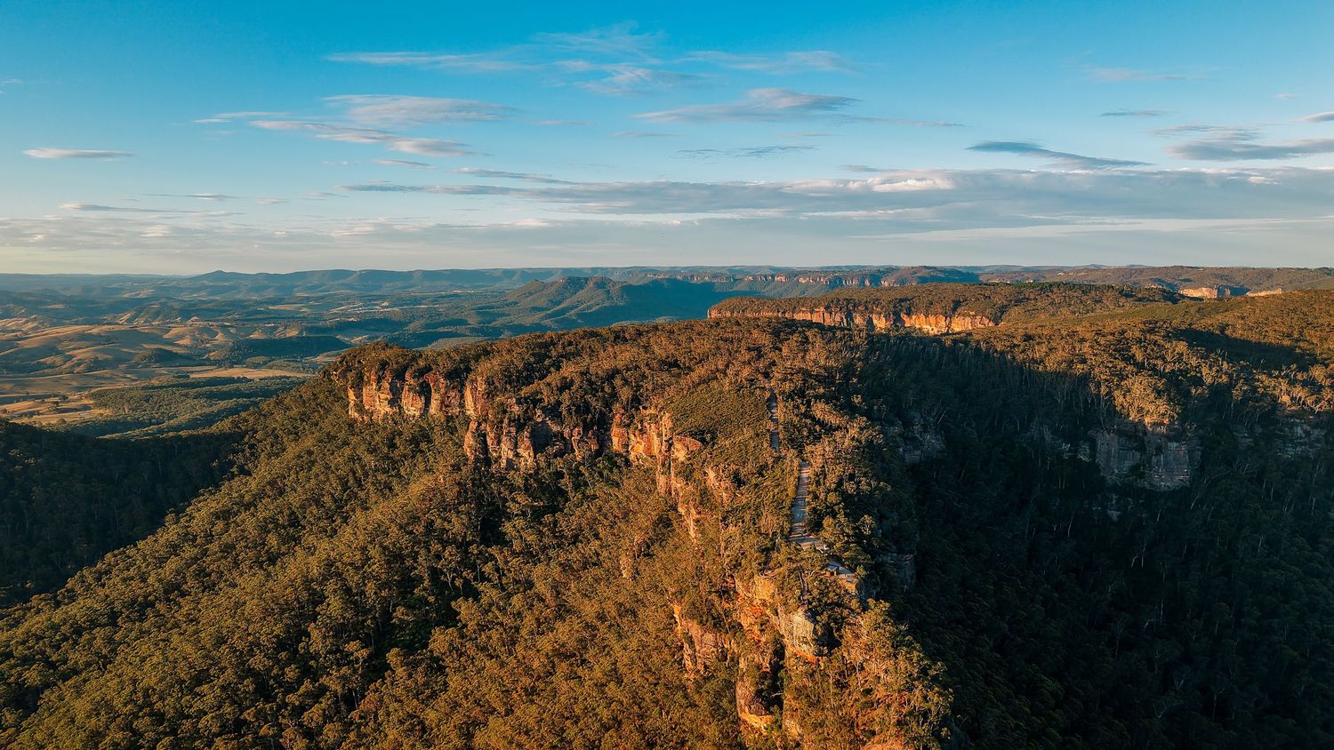 Sweeping panoramic vista of blue mountains and valleys under a bright azure sky.